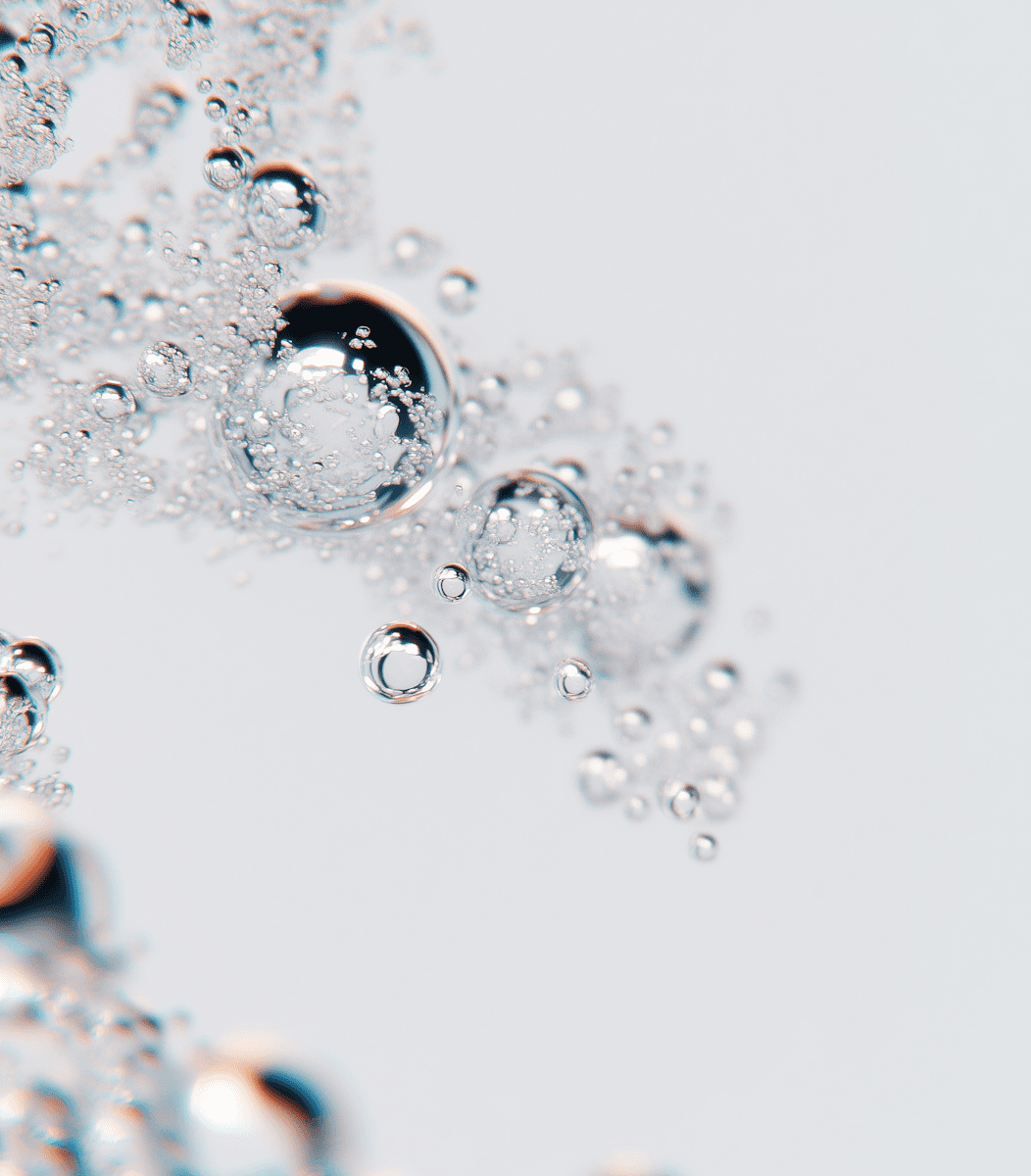 Macro of clear effervescent bubbles in water on a soft gray background—sparkling, minimal texture for clean skincare aesthetic.